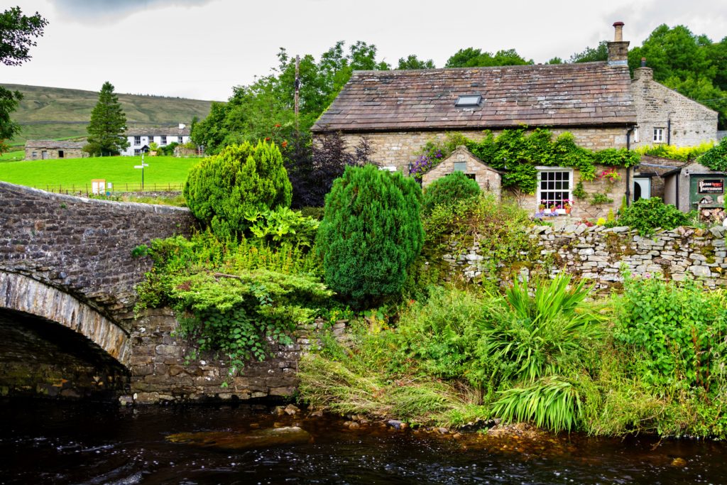 YORKSHIRE DALES, AUGUST 25, 2016: Old stone house by the river in Yorkshire Dales National Park, England, United Kingdom